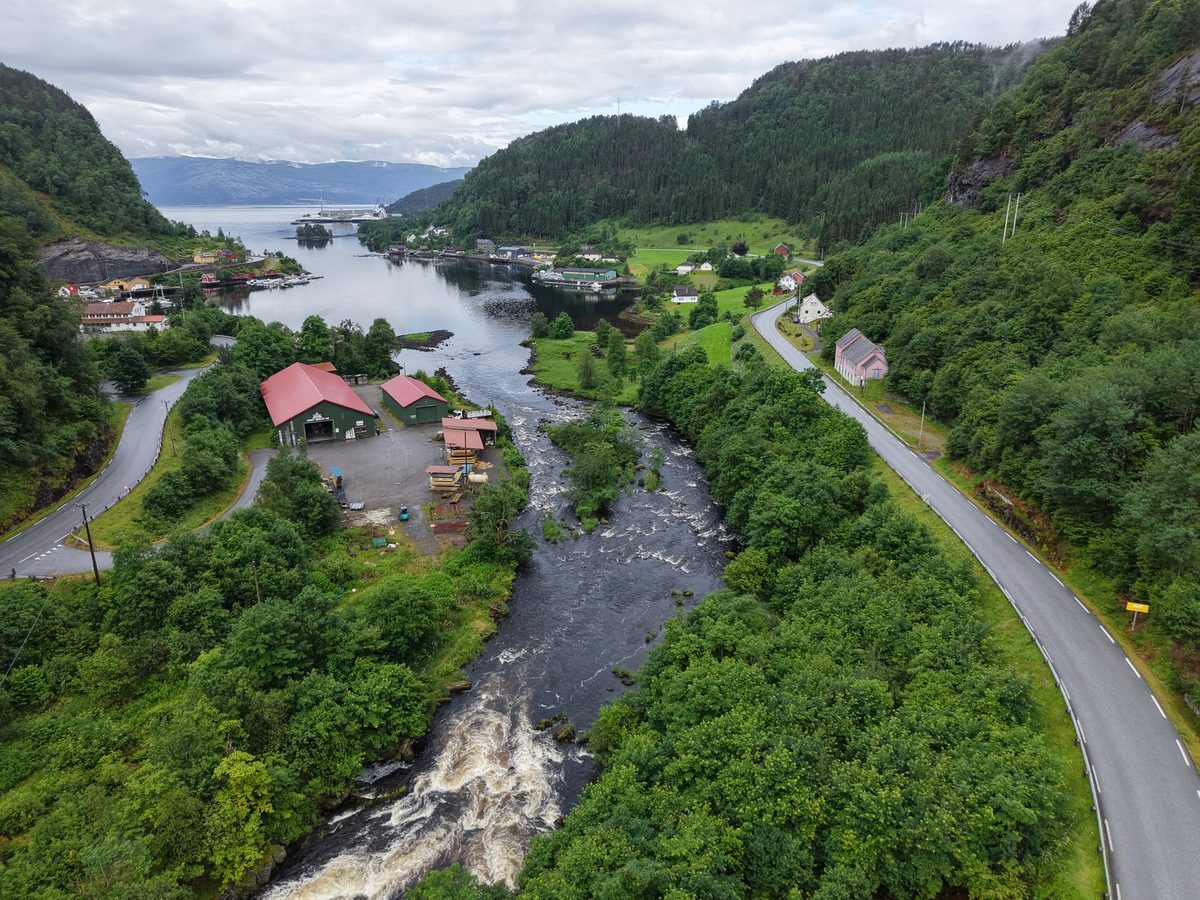 Tettsted langs vassdrag med vei sett fra drone